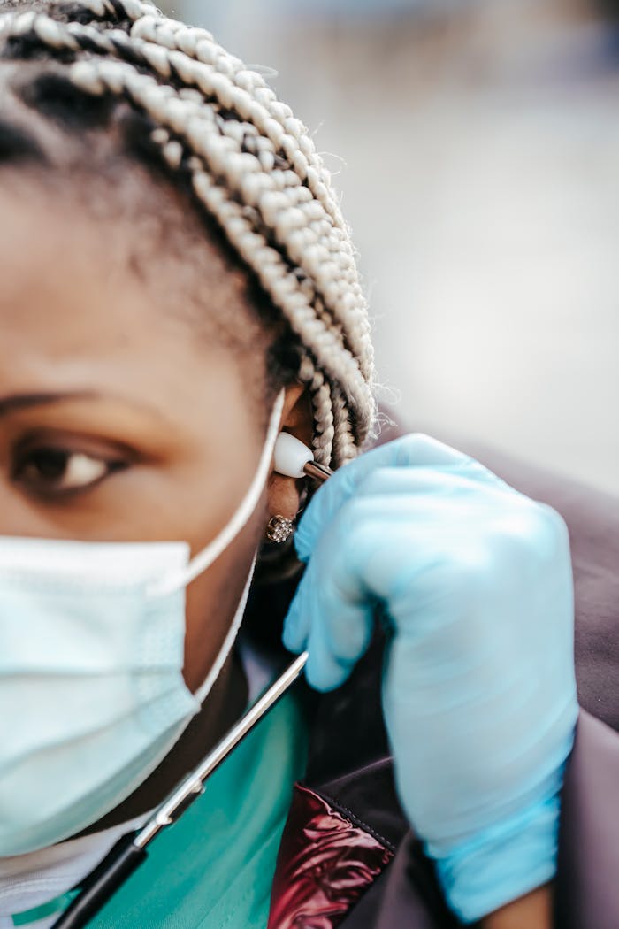 Crop adult African American female doctor in medical clothes and protective mask with gloves and stethoscope in daytime