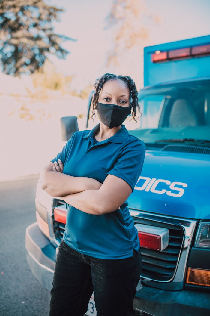 Female EMT with mask beside ambulance, ready for action.